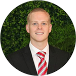 A man in suit and tie standing next to green wall.